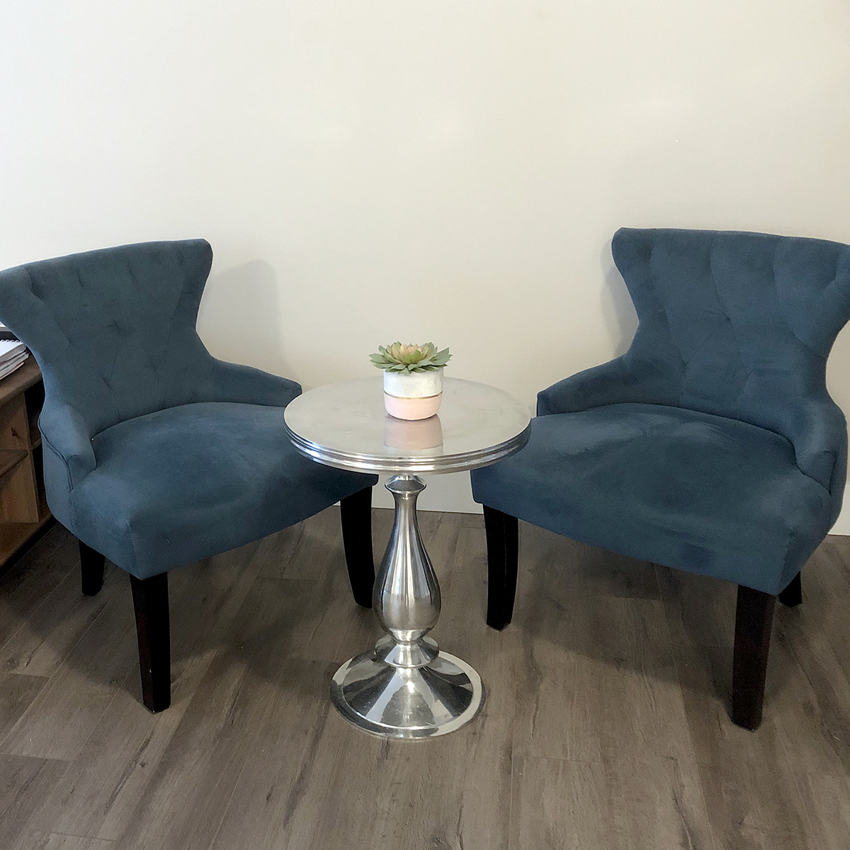Two blue fabric armchairs next to a circular silver table at Tanglewood Counselling
