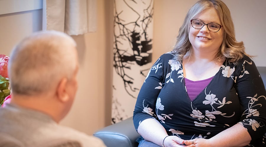 Dee-Anne Doak sitting with a client, taken from over the shoulder of the client