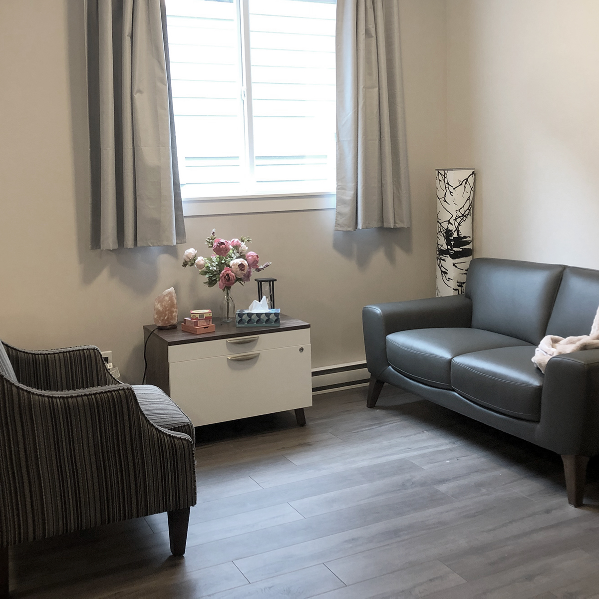 Couch and chair inside Tanglewood Counselling, arranged near a window with beige curtains